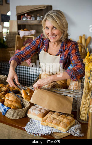 Weibliche Personal Verpacken Donut in Papiertüte am Schalter im Bäckerladen Stockfoto