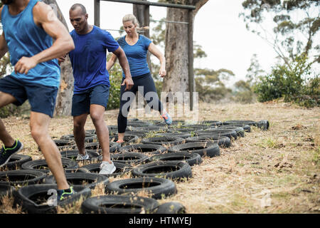 Menschen, die Reifen-Hindernis-Parcours-Training im Boot camp Stockfoto