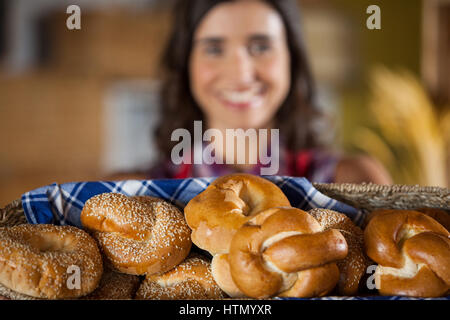 Weibliche Personal holding Weidenkorb an verschiedenen Brotsorten am Schalter in Bäckerei Stockfoto