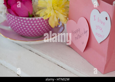 Nahaufnahme der Papiertüte mit Meldung und frische Blumen auf Holzuntergrund Stockfoto