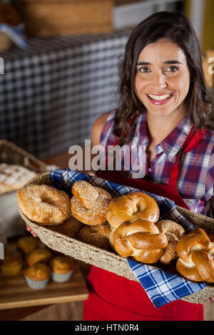 Weibliche Personal holding Weidenkorb an verschiedenen Brotsorten am Schalter in Bäckerei Stockfoto