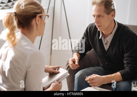 Psychologe-Sitzung. Deprimiert pessimistisch angenehmer Mensch seinem Therapeuten betrachten und teilen seine Probleme mit ihr während einer Depression leiden Stockfoto