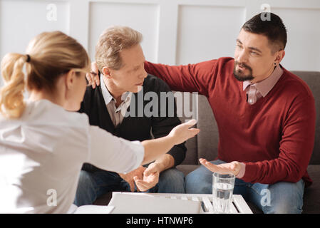 Haben Sie eine Diskussion. Angenehme intelligente weibliche Psychologe zeigte auf den Mann und auf ihn zu hören, während der Erörterung der Probleme ihrer Patienten Stockfoto