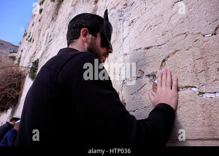 Ein religiöser Jude, der Batman Maske trägt und während des jüdischen Festivals Purim in der Westmauer oder Kotel in der Altstadt von Ostjerusalem Israel betet Stockfoto