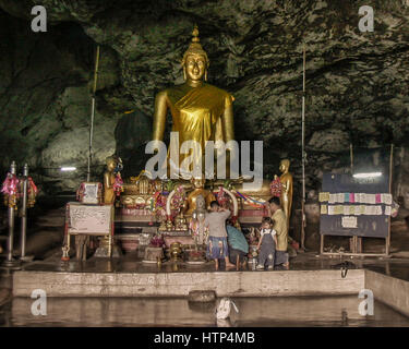 Kanchanaburi, Thailand. 15. November 2006. Eine thailändische Familie in Tham Krasae (Krasae Höhle), ein Tempel-Höhle mit einer riesigen goldenen Buddha-Statue und zahlreiche heilige Buddha-Figuren. Es blickt auf den Khwae Noi Fluss nahe dem Wang-Pho-Bahnhof im Westen Thailands. Im 2. Weltkrieg diente es als Campingplatz und Feldlazarett für japanische Soldaten verantwortlich für die alliierten Kriegsgefangenen Bau der berüchtigten Thailand-Burma-Eisenbahn. Bildnachweis: Arnold Drapkin/ZUMA Draht/Alamy Live-Nachrichten Stockfoto