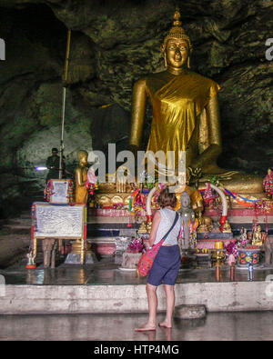 Kanchanaburi, Thailand. 15. November 2006. Eine weibliche Touristen in Tham Krasae (Krasae Höhle), ein Tempel-Höhle mit einer riesigen goldenen Buddha-Statue und zahlreiche heilige Buddha-Figuren. Es blickt auf den Khwae Noi Fluss nahe dem Wang-Pho-Bahnhof im Westen Thailands. Im 2. Weltkrieg diente es als Campingplatz und Feldlazarett für japanische Soldaten verantwortlich für die alliierten Kriegsgefangenen Bau der berüchtigten Thailand-Burma-Eisenbahn. Bildnachweis: Arnold Drapkin/ZUMA Draht/Alamy Live-Nachrichten Stockfoto