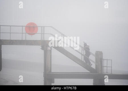 Aberystwyth, Wales, UK. 14. März 2017. UK-Wetter: Menschen zu Fuß entlang der Promenade werden durch den Nebel in der Stadt von Aberystwyth Resort an der Westküste von Wales verdeckt, wie eine dicke Decke des grauen Meeres Kaltnebel wirbelnden kommt in aus der irischen See heute Nachmittag. Bildnachweis: Keith Morris/Alamy Live-Nachrichten Stockfoto