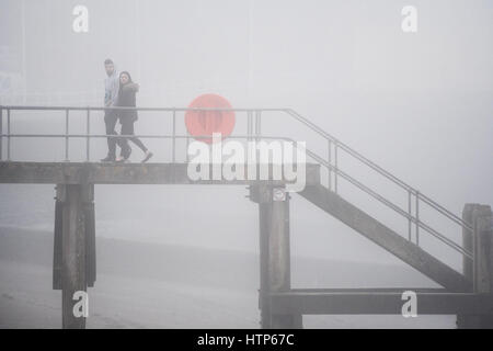Aberystwyth, Wales, UK. 14. März 2017. UK-Wetter: Menschen zu Fuß entlang der Promenade werden durch den Nebel in der Stadt von Aberystwyth Resort an der Westküste von Wales verdeckt, wie eine dicke Decke des grauen Meeres Kaltnebel wirbelnden kommt in aus der irischen See heute Nachmittag. Bildnachweis: Keith Morris/Alamy Live-Nachrichten Stockfoto
