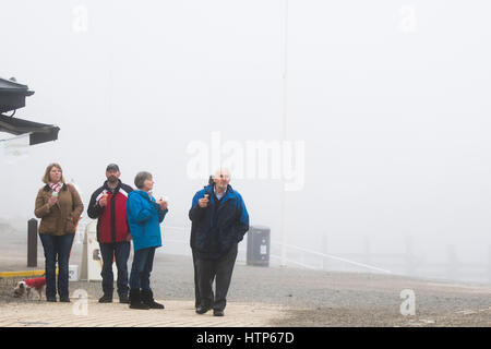 Aberystwyth, Wales, UK. 14. März 2017. UK-Wetter: Menschen essen ihr Eis im Nebel in der Stadt von Aberystwyth Resort an der Westküste von Wales sowie eine dicke Schneedecke grauen Meer Kaltnebel wirbelnden kommt in aus der irischen See am Nachmittag. Bildnachweis: Keith Morris/Alamy Live-Nachrichten Stockfoto