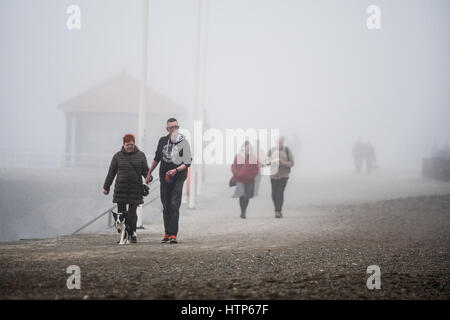 Aberystwyth, Wales, UK. 14. März 2017. UK-Wetter: Menschen zu Fuß entlang der Promenade werden durch den Nebel in der Stadt von Aberystwyth Resort an der Westküste von Wales verdeckt, wie eine dicke Decke des grauen Meeres Kaltnebel wirbelnden kommt in aus der irischen See heute Nachmittag. Bildnachweis: Keith Morris/Alamy Live-Nachrichten Stockfoto