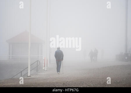 Aberystwyth, Wales, UK. 14. März 2017. UK-Wetter: Menschen zu Fuß entlang der Promenade werden durch den Nebel in der Stadt von Aberystwyth Resort an der Westküste von Wales verdeckt, wie eine dicke Decke des grauen Meeres Kaltnebel wirbelnden kommt in aus der irischen See heute Nachmittag. Bildnachweis: Keith Morris/Alamy Live-Nachrichten Stockfoto