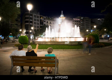 Drei ältere Menschen sitzen auf einer Bank zurück zu Kamera Blick auf den beleuchteten Brunnen in der Plaza del Campilo an einem Sommerabend in Granada Spanien Stockfoto