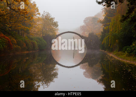 Rakotzbrücke (Teufelsbrücke) im frühen Morgennebel im Herbst, Kromlau, Deutschland Stockfoto