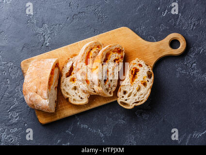 Geschnittenem Brot Ciabatta mit Käse auf Schneidebrett auf dunklem Hintergrund Stockfoto