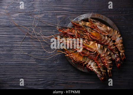 Rohe frische Tiger Garnelen Garnelen in Metallplatte auf verbrannte schwarze Holz Hintergrund Stockfoto