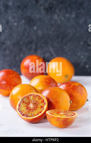 In Scheiben geschnitten und ganz reife saftige sizilianischen Blut Orangen Früchte über weiße und graue Betontextur Hintergrund. Textfreiraum Stockfoto