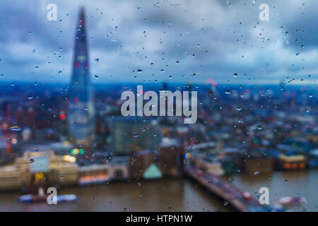 London hinter dem Wassertropfen und Themse bei Sonnenuntergang vor einem bewölkten Himmel. London, Vereinigtes Königreich. Stockfoto