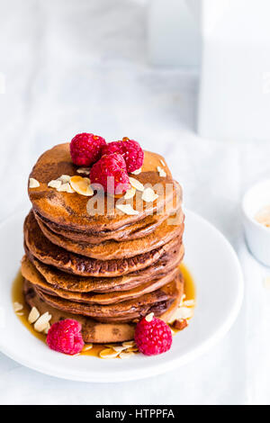 Stapel von eifreie Pfannkuchen mit Himbeeren, gerösteten Mandeln und Ahornsirup Stockfoto