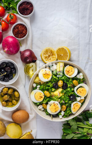 Mediterraner Kartoffelsalat mit Kräutern und hart gekochten Eiern, begleitet von schwarze und grüne Oliven, roten Zwiebeln, Sumach und Paprika Flocken Eunhye Stockfoto