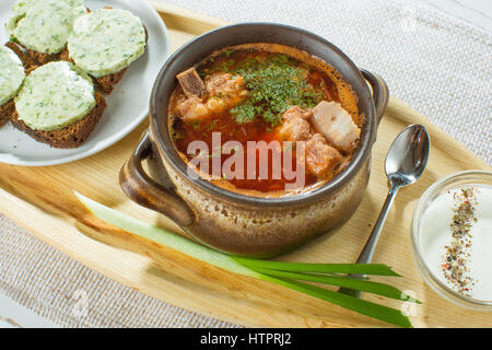 Roten Borschtsch-Suppe in grau Schüssel mit saurer Sahne, Fleisch, Zwiebel, Petersilie, Draufsicht, isolated on White. Traditionellen ukrainischen russischen Gemüse Stockfoto