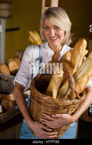 Weibliches Personal holding Korb Baguettes Bäckerei Abschnitt des Supermarktes Stockfoto