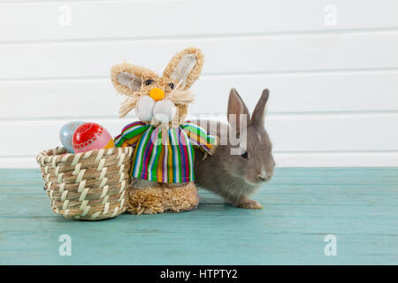 Ostereier auf Weidenkorb mit Osterhasen und Spielzeug aus Holz Hintergrund Stockfoto