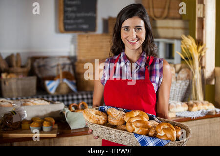 Weibliche Personal holding Weidenkorb an verschiedenen Brotsorten am Schalter in Bäckerei Stockfoto