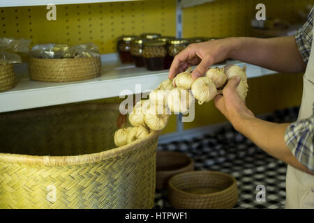 Mittelteil des Personals setzen Knoblauch in Weidenkorb im Markt Stockfoto