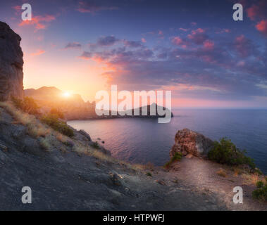 Berglandschaft bei Sonnenuntergang. Schöne Aussicht vom Berg auf das blaue Meer, Kap, Hügeln, Felsen und bunten Himmel mit orange Sonnenlicht in das lösen Stockfoto
