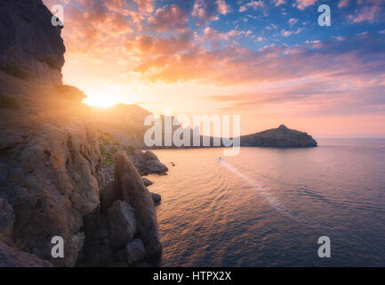 Berglandschaft bei Sonnenuntergang. Schöne Aussicht vom Hügel auf das blaue Meer, Kap, Klippen und bunten sonnigen Himmel mit orange Wolken am Abend. TR Stockfoto
