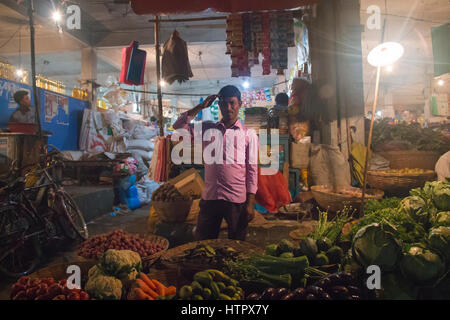 SRIMANGAL, Bangladesch - Februar 2017: Mann mit einen kleinen Laden mit Gemüse auf dem zentralen Bazar Markt in Srimangal, Bangladesch Stockfoto