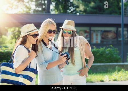 Drei attraktive Mädchen Betrachten von Fotos auf Ihrer Kamera am Sommer, Urlaub, Mädchen Freunde auf ihrer Reise Urlaub Stockfoto