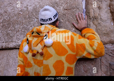 Ein religiöser Jude tragen typische weiße "Na Nacher" Stil Kippa "Breslov" mit dem Satz verwoben, und eine Giraffe Kostüm beten während des jüdischen Festivals von Purim in der Klagemauer oder Kotel in der Altstadt Ost-Jerusalem Israel Stockfoto