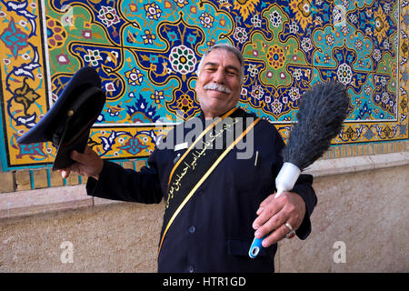 Eine religiöse Attendant entspannt mit einem Staubtuch am Eingang des Shah Cheragh Heiligtum in Shiraz, Provinz Fars, Iran Stockfoto
