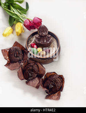 Ostern-Zusammensetzung der Huhn gemacht Schokolade, sitzen in einem Nest, bemalten Eiern und Schokolade Cupcakes auf weißem Hintergrund Stockfoto