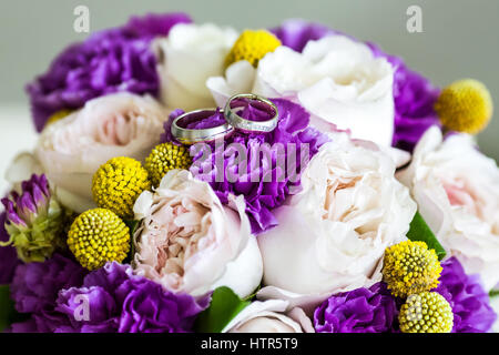 Trauringe auf Bouquet von rosa und lila Blumen in blauer Vase, Nahaufnahme Stockfoto