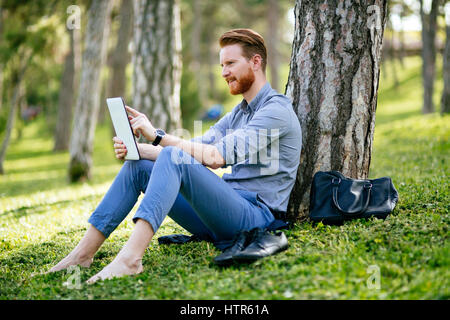 Gut aussehend Geschäftsmann mit TabletPC im park Stockfoto