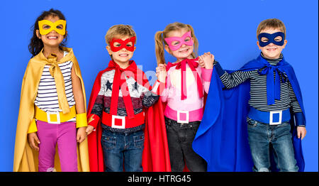 Kleine Kinder kleiden Superhelden an den Händen halten Stockfoto