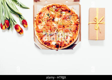 Pizza-Box, roten Tulpen und Geschenk-Box, die auf weißen Tisch, Ansicht von oben Stockfoto