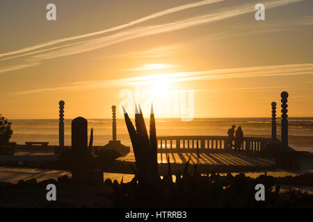 Schönes Bild am Strand von Aglou Plage in Marokko betroffen das letzte Sonnenlicht des Tages, während zwei Personen auf den Horizont blicken. Stockfoto