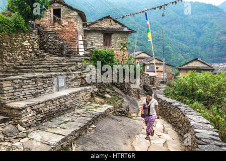 Eine Frau geht durch eine ländliche Gasse im Sidhane Dorf an den Hängen des Panchase-Gebirges, Nepal. Stockfoto