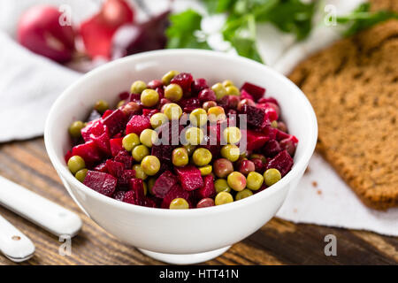 Rote Beete Salat in Schüssel geben. Russische Rote Beete Salat mit rote Beete, Kartoffeln, Karotten, Erbsen und Öl-dressing Stockfoto