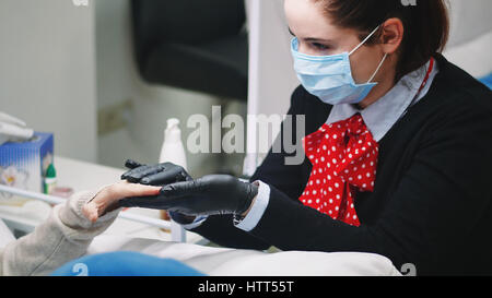 Closeup Aufnahme einer Frau in einem Nagelstudio erhalten eine Maniküre von einer Kosmetikerin mit Nagelfeile. Stockfoto