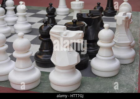 Große schwarze und weiße Schachfiguren auf einer Steinplatte. Stockfoto