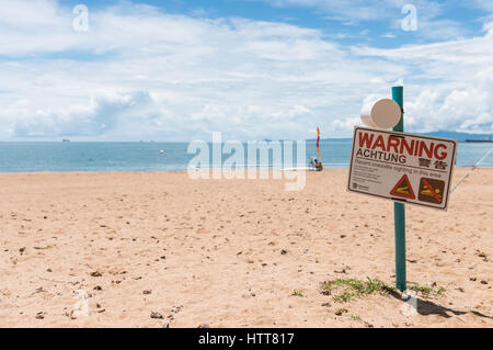 Warnzeichen für Krokodil Sichtung auf The Strand Beach, Townsville, Australien mit Schwimmen Netze im Hintergrund Stockfoto