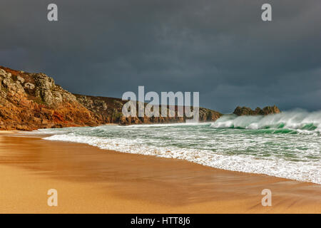 Blick auf Logan Rock von Porthcurno Strand. 28. Februar 2017. Stürmischen Wolken vorbei. Mit schönen Winter Sonnenlicht und einer Flut. © Stockfoto