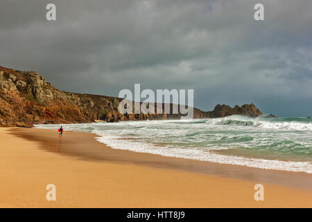 Blick auf Logan Rock von Porthcurno Strand. 28. Februar 2017. Stürmischen Wolken vorbei. Mit schönen Winter Sonnenlicht und einer Flut. © Stockfoto