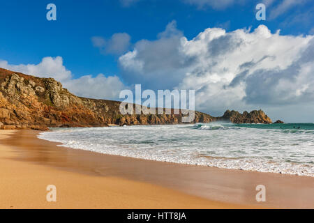 Blick auf Logan Rock von Porthcurno Strand. 28. Februar 2017. Stürmischen Wolken vorbei. Mit schönen Winter Sonnenlicht und einer Flut. © Stockfoto