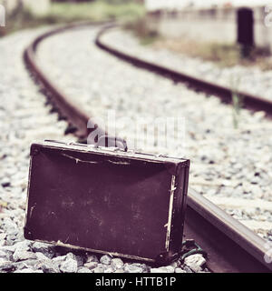 einen alten braunen Koffer neben den Bahngleisen Stockfoto