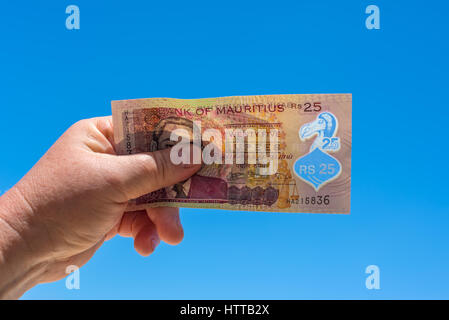 Hand halten Rechnung gegen den blauen Himmel - 25 mauritische Rupien-Banknote mit traditionellen Dodo-Vogel drauf abgebildet Stockfoto